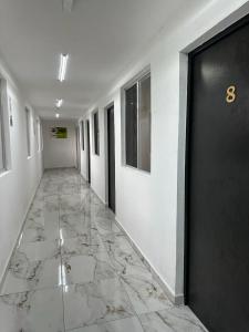 un couloir avec une porte noire et un sol en marbre dans l'établissement Hotel Villa 12 Orquídeas, à San Juan del Río