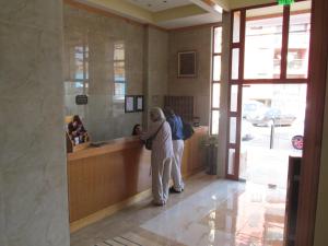two people standing at a counter in a lobby at Hotel MST Colonial in Iquique