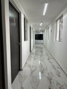 un pasillo vacío con puerta y suelo de mármol en Hotel Villa 12 Orquídeas, en San Juan del Río