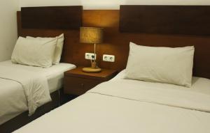 Habitación de hotel con 2 camas y mesita de noche con lámpara en Hotel Graha Kinasih Kotabaru en Yogyakarta