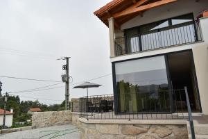 Casa con balcón con sombrilla en Casinhas da eira caramulo turismo rural, en Arca