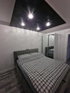 een slaapkamer met een bed en een plafond met verlichting bij Apartament Plażowa in Międzywodzie