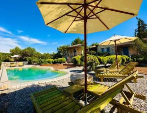 a patio with chairs and an umbrella and a pool at Strofilia Stone Residences in Volimes