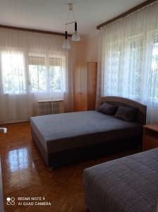 a bedroom with two beds and two windows at Mátyás király Apartman in Vonyarcvashegy