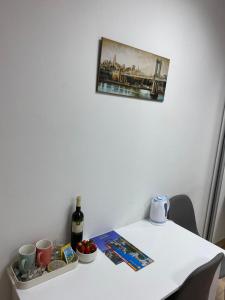 - une table blanche avec une bouteille de vin et une photo sur le mur dans l'établissement Capital apartments - CITY CENTRE, à Mostar