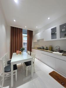 cocina blanca con mesa blanca y sillas en Mộc Homestay 2 phòng ngủ en Ấp Ðông An (1)