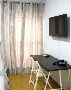 Habitación con mesa y TV en la pared. en Hostal Villa, en Chiclana de la Frontera