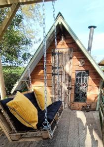 a porch swing in front of a log cabin at Down The Rabbit Hole in Waterfall