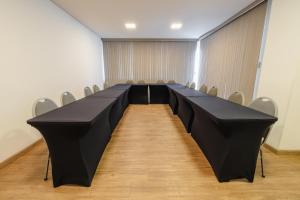 einen langen schwarzen Tisch in einem Zimmer mit Stühlen in der Unterkunft Hotel Caiuá Lago Umuarama in Umuarama
