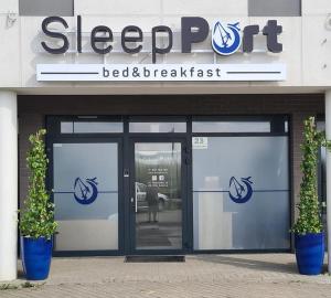 a door to a bed and breakfast building with two plants at Sleep Port in Gdańsk