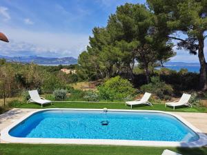 a swimming pool with two lawn chairs at BASTIDE PRESQU ILE DE GIENS SUPERBE VUE MER PISCINE in Hyères