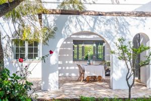 uma arcada com uma mesa numa casa branca em ONLY FAMILIES Villa and Guest House with Private Pool em Chiclana de la Frontera