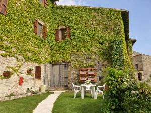 a table and chairs in front of a building with ivy at Il borgo di Cornillo in Meggiano