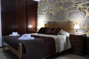 a bedroom with a bed and a stone wall at Casa da Ramada in Campo do Gerês