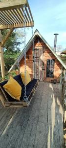 a swing on a deck in front of a cabin at Down The Rabbit Hole in Waterfall