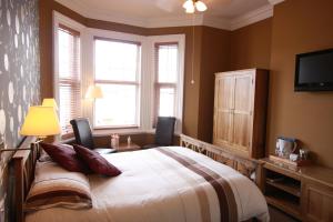 1 dormitorio con 1 cama con 2 sillas y TV en Brentwood Guest House en York
