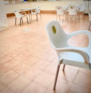 RoNi RoOms في سالو: كرسي أبيض في غرفة مع طاولات وكراسي