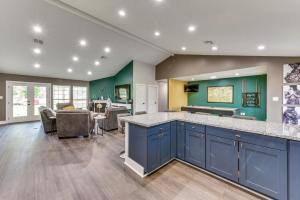 a kitchen with blue cabinets and a living room at Luxe Lake Charles Escape with Home Theater! in Lake Charles