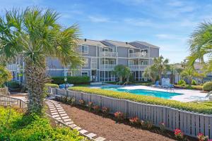 an apartment complex with a swimming pool and palm trees at The Sand Dollar at Sea Cloisters in Myrtle Beach