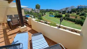 balkon z krzesłami i widokiem na pole golfowe w obiekcie Sunny Golf View Miraflores w mieście Sitio de Calahonda