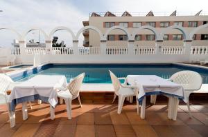 una piscina con 2 mesas y sillas junto a una piscina en Hotel Apartamentos Vibra Lux Mar, en Ibiza