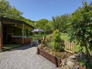 - un jardin avec une table et un parasol sur une maison dans l'établissement Brook Lodge, à Llandysul