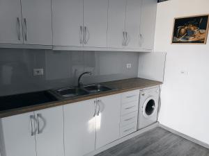 a white kitchen with a sink and a washing machine at Arber's Home in Sarandë