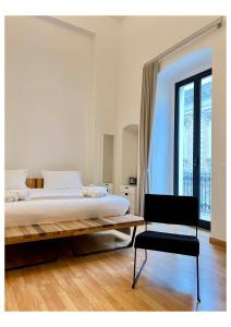 a white bedroom with a bed and a chair at Imago Plus Hotel in Bari