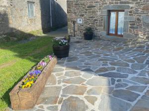 Una pasarela de piedra con un banco con flores. en Casa da Cota, en Monterroso