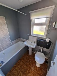 a bathroom with a tub and a toilet and a sink at Rosie's Place in Great Yarmouth