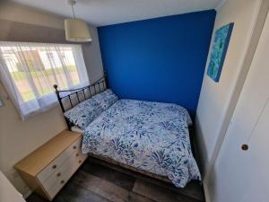 a small bedroom with a bed and a blue wall at Rosie's Place in Great Yarmouth