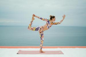 Una donna che fa una posa yoga sulla spiaggia di Hotel Villa Maria a Ischia