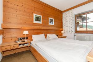 een slaapkamer met een bed en een houten muur bij Ferienwohnung Dominik in Reit im Winkl