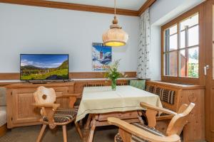 een eetkamer met een tafel en stoelen en een televisie bij Ferienwohnung Dominik in Reit im Winkl