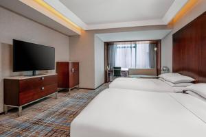 a hotel room with two beds and a flat screen tv at Renaissance Shanghai Zhongshan Park Hotel in Shanghai