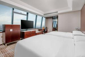 a hotel room with a bed and a flat screen tv at Renaissance Shanghai Zhongshan Park Hotel in Shanghai