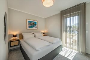 ルブミンにあるLubminer Meerblick Apartmentsのベッドと窓のある白い寝室