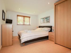 a bedroom with a bed and a dresser and a window at Pebbles in Torpoint