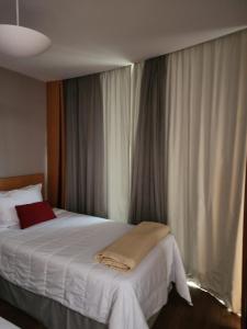 a bedroom with a bed with white sheets and curtains at FLAT Ibirapuera Jardins ótima localização com garagem inclusa! in Sao Paulo