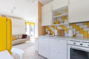 a kitchen with white cabinets and yellow tiles on the wall at Yellow Studio Paupys in Vilnius