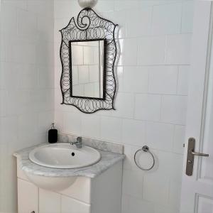 Baño blanco con lavabo y espejo en VILLA KIKA ZARZIS, LOCATION CHAMBRES D'HÔTES en TUNISIE en Zarzis