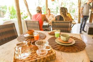 a table with plates and cups and people sitting at a restaurant at Casa La Luna - Arraial D'Ajuda in Arraial d'Ajuda