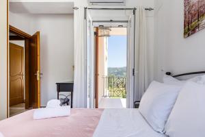 a bedroom with a white bed and a balcony at Glyna House in Skopelos Town