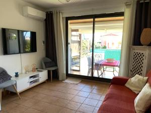 sala de estar con sofá y puerta corredera de cristal en Appartement rue de l'amarrage à PORT GRIMAUD avec Terrasse vue canaux et garage en Grimaud