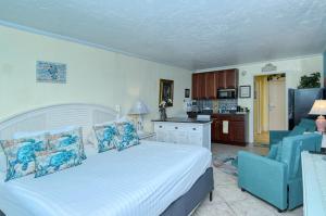 a bedroom with a large white bed and a kitchen at Waterfront Room, Heated Pool, Tiki Bar & Grill in Sarasota