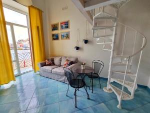 ein Wohnzimmer mit einer Wendeltreppe sowie einem Tisch und Stühlen in der Unterkunft Maridea - In Riva al Mare in Ponza