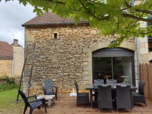 un patio con mesa y sillas frente a un edificio de piedra en Les gîtes de Louise, en Archignac