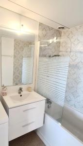 uma casa de banho com um lavatório, uma banheira e um espelho. em Résidence Katikias - vue mer em Bandol