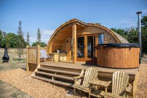 a wooden cabin with two chairs and a hot tub at Barnhorn Glamping in Hooe