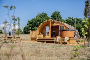 a cabin in a field with a table and chairs at Barnhorn Glamping in Hooe